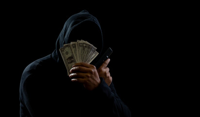 Hacker spy man hands wearing a black shirt, sitting on a chair and a table, is a thief, holding...