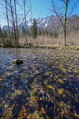 Idyllic creek with clear cold water and snow covered mountains in the background. 