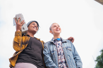 Two young urban stylish women listening to music from the boombox and making rap rhymes. Concept: Lifestyle, urban music, singing