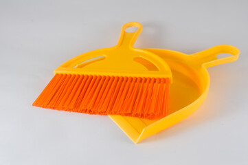 orange broom and dustpan on white background