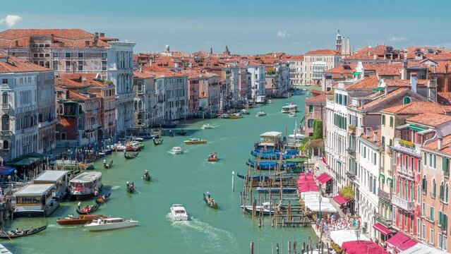 Aerial view on central busy canal in Venice timelapse, on both sides masterpieces of Venetian architecture, with lots of tourists sailing on gondolas and boats. Blue cloudy sky at summer day