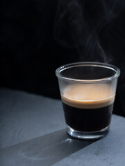 Espresso coffee on a transparent glass, on a black background