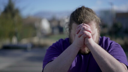 One Spiritual young man raising arms in the air asking for God help. Dramatic person praying with hands clenched feeling grateful. Hope and Gratitude concept