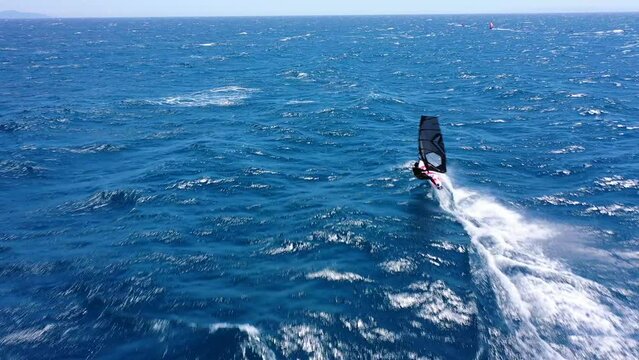 Aerial drone video of fit unidentified wind surfer racing in tropical exotic open ocean bay with deep blue wavy sea