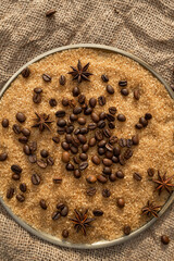 Coffee beans on brown sugar cane, lying on a bronze plate, against a background of coarse burlap. Background picture in brown tones