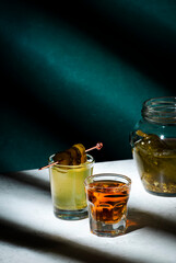 Pickleback, alcoholic cocktail made from cucumber pickle and whiskey in small shot glasses. Hard light and shadows