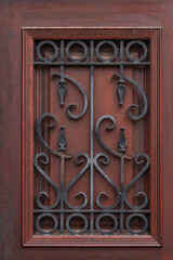 close-up of a beautiful black forged fence on a window with shutters in a old house