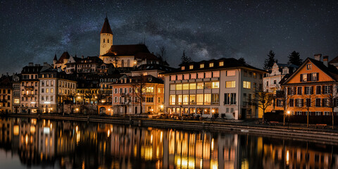 Thun, Switzerland. Cityscape image of beautiful city of Thun with the reflection of the city in the Aare river at night with amazing milky way arch. Travel concept.