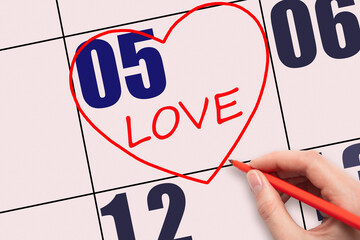 5th day of the month. Hand writing text LOVE and drawing a red heart on a pink calendar date.