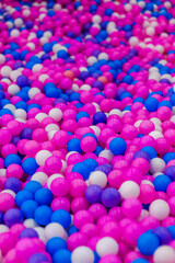 Background, texture of a large pile of colored, multi-colored round plastic small balls on the playground for children's games. Photography, top view, copy space, childhood concept, macro.