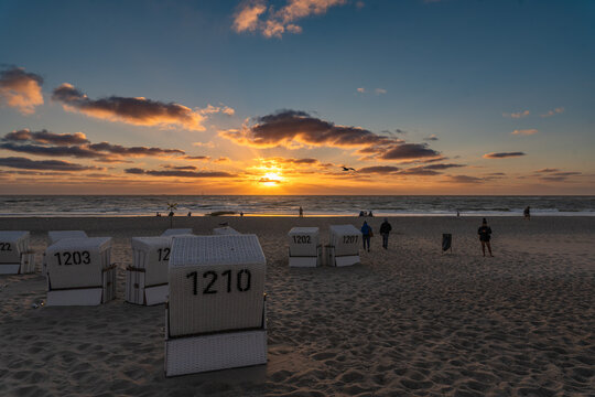 A group of beach chairs with tourists and the beach view into the sunset, Baltic Sea, Sylt, Germany.