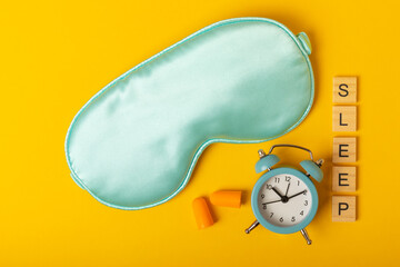 Sleep mask and alarm clock on a yellow background. Sweet dreams concept. The concept of rest, sleep...