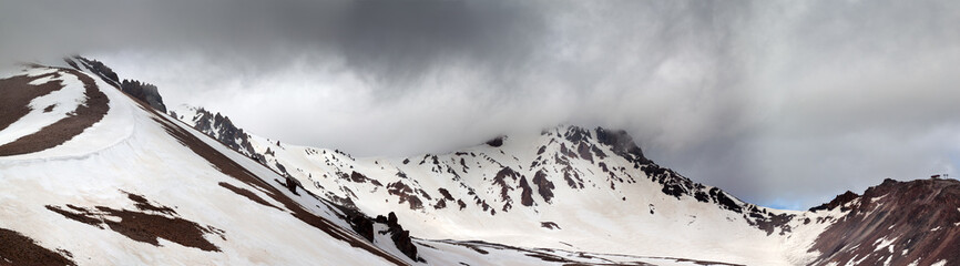 Panorama of snowy mountains before rain