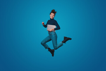 Obraz premium Full length body size of excited positive woman wearing jeans holding notebook going conference isolated on blue color background. Modern lifestyle. Blue