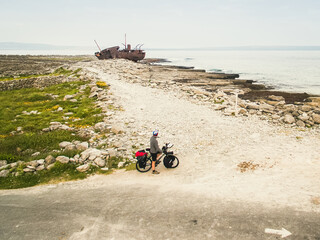 Aerial view tourist with bicycle by plassey shipwreck in background. Popular tourist landmark and...