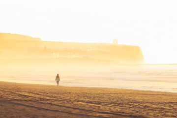 Woman walk on golden sand beach of portstewart strand by with castlerock lighthouse backgorund....