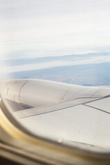 Fototapeta na wymiar Plane window view on blue sky, clouds, mountains. Scenes from an airplane trip.