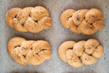 Homemade braided bread rolls made from wholegrain spelt flour on a baking sheet