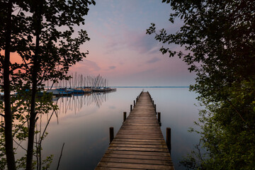 Fototapeta na wymiar Steinhuder Meer north shore with jetty at sunrise - view to the south on the sailing boats. the largest lake of northwestern Germany and it is a nationwide tourist destination