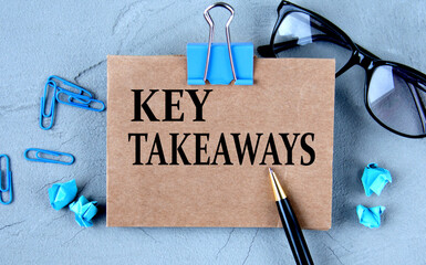 KEY TAKEAWAYS - words on brown paper on the background of glasses, pens and paper clips