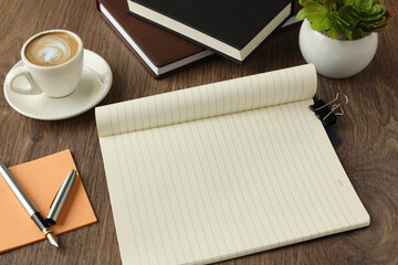 Flat lay, top view of open notebook and other supplies. coffee cup and plant sticker and pen