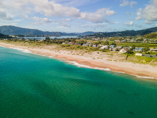 Aerial flight above Tairua ocean beach in New Zealand