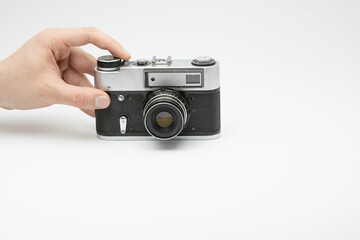 Hand pressing the shoot button on a vintage film camera isolated on white backgorund. Hand taking picture with an old film camera. Finger pressing the shoot button on a film camera 