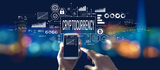 Cryptocurrency theme with person using a smartphone in a city at night