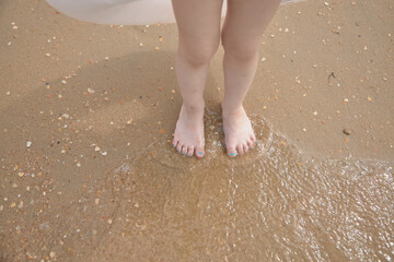 Feet are on the sand right on the beach, sea summer vacation.
