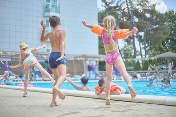 Happy little children listen to music, dance, sing songs, have fun in the summer pool, relax by the sea. Morning workout exercise.