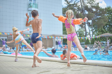 Obraz premium Happy little children listen to music, dance, sing songs, have fun in the summer pool, relax by the sea. Morning workout exercise.