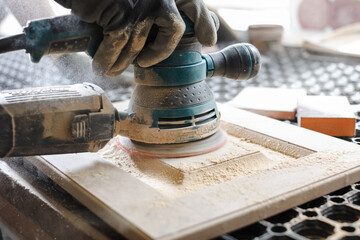 Carpenter with grinder. Man grinding planks of wood for home construction