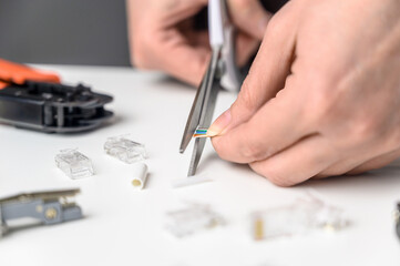 A woman's hand cuts the ends of the wire for a utp ethernet network cable plug. Internet communications concept.