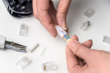 A woman's hand inserts an internet cable into a clamp connector. utp ethernet network cable plug. The concept of internet communications.
