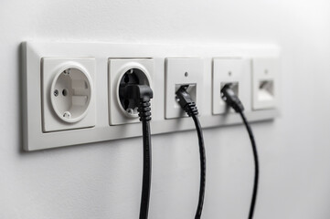 electrical and internet socket on a white wall in the room. Five electrical and ethernet plugs with...