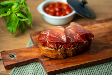 sandwich with jamon serrano paleta iberico ham, arugula, rosemary on stone slate black...