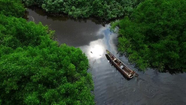 Amazon river crossed by boat with natives coming out of the thick Amazon jungle