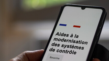 An entrepreneur subscribing to an aid on a phone. French text : Aid for modernization of control systems.. Text in French.