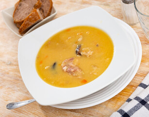 Appetizing hot pea soup with smoked meats served with slices of bread