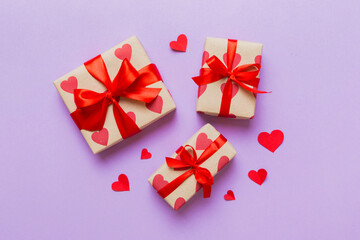 Top view photo of valentine day decorations gift box with red ribbon bow on colored background. Holiday gift boxes with top view