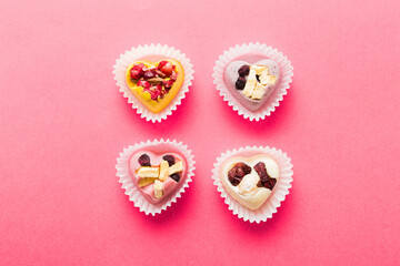 chocolate sweets in the form of a heart with fruits and nuts on a colored background. top view with space for text, holiday concept