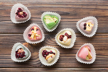 chocolate sweets in the form of a heart with fruits and nuts on a colored background. top view with space for text, holiday concept
