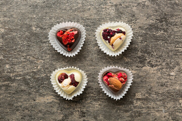 chocolate sweets in the form of a heart with fruits and nuts on a colored background. top view with space for text, holiday concept