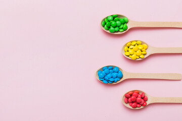 delicious colorful sweet candies on spoon on colored background . Confectionery decor top view with copy space