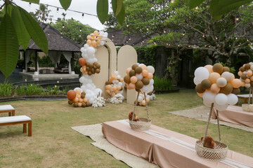 Creative gender neutral baby shower or birthday decoration in the garden. Bohemian style outdoor event set up with balloons. White cream peach caramel balloon arch kit.