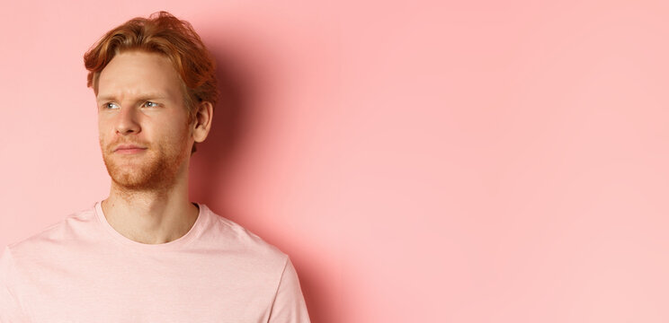 Close Up Of Skeptical And Unamused European Man, Smirk With Judgemental Face, Looking Left At Banner, Standing Over Pink Background