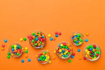 different colored round candy in bowl and jars. Top view of large variety sweets and candies with...