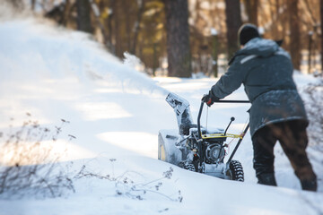 Process of removing snow with portable blower machine, worker dressed in overall workwear with gas snow blower removal on the street during winter