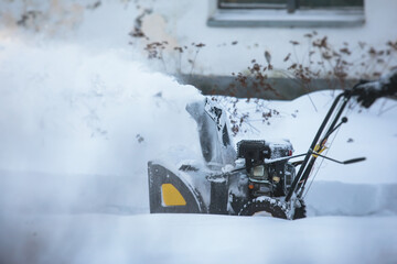 Process of removing snow with portable blower machine, worker dressed in overall workwear with gas...