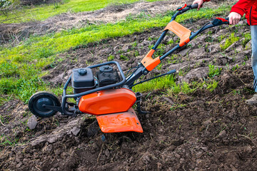 Orange professional cultivator or tiller on untreated soil before plowing. Treatment of virgin land...
